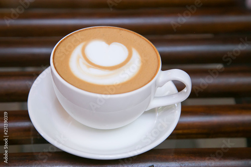 coffee cuppacino on wooden table in white cup with white heart froth photo