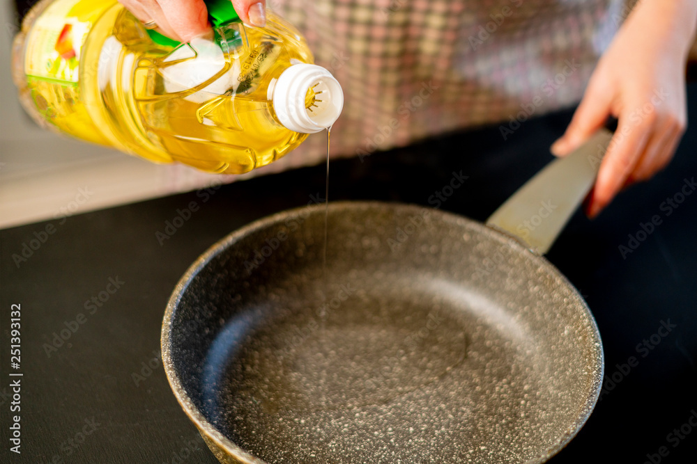 woman pouring oil on the frying pan