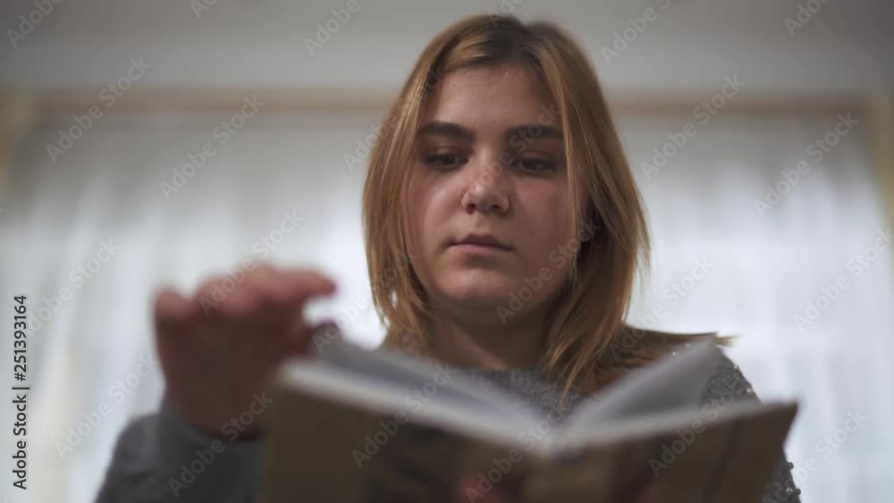 Close up portrait plus size girl reading book sitting at sofa in home. Chubby woman holding book in hands. Leisure of smart plus size lady at home Close up portrait plus size girl reading book sitting at sofa in home. Chubby woman holding book in hands. Leisure of smart plus size lady at home