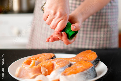 woman pouring spices on a fish