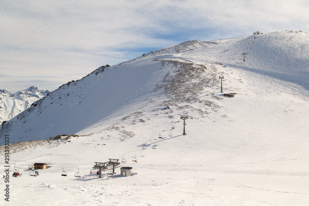 DOMBAI, RUSSIA, FEBRUARY 27, 2018: Panoramic view on a chairlift and a snowy mountain on a sunny winter day DOMBAI, RUSSIA, FEBRUARY 27, 2018: Panoramic view on a chairlift and a snowy mountain on a sunny winter day