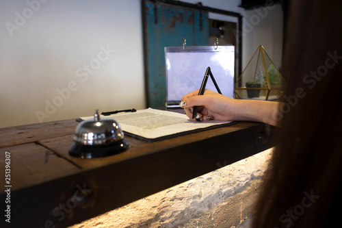 Close up of women putting signing and filling up form at hotel reception.