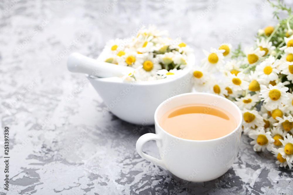 Cup of tea with chamomile flowers on grey background Cup of tea with chamomile flowers on grey background