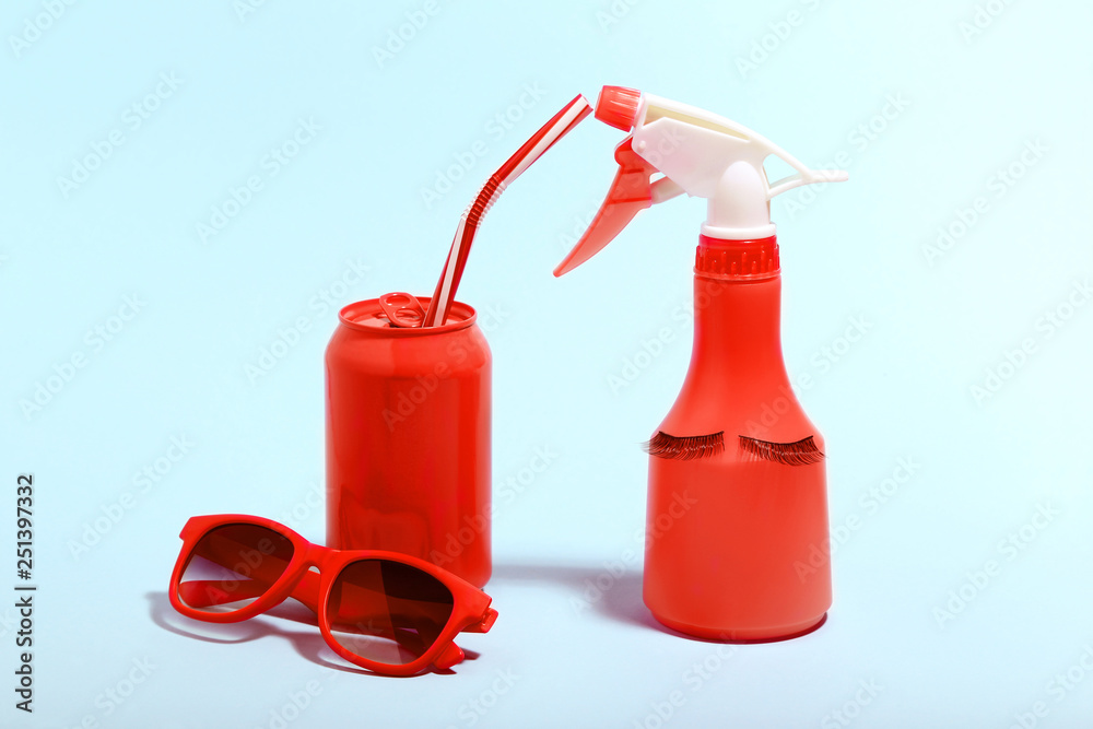 Obraz premium Aluminum can with sunglasses and spray bottle on blue background. Minimalism concept