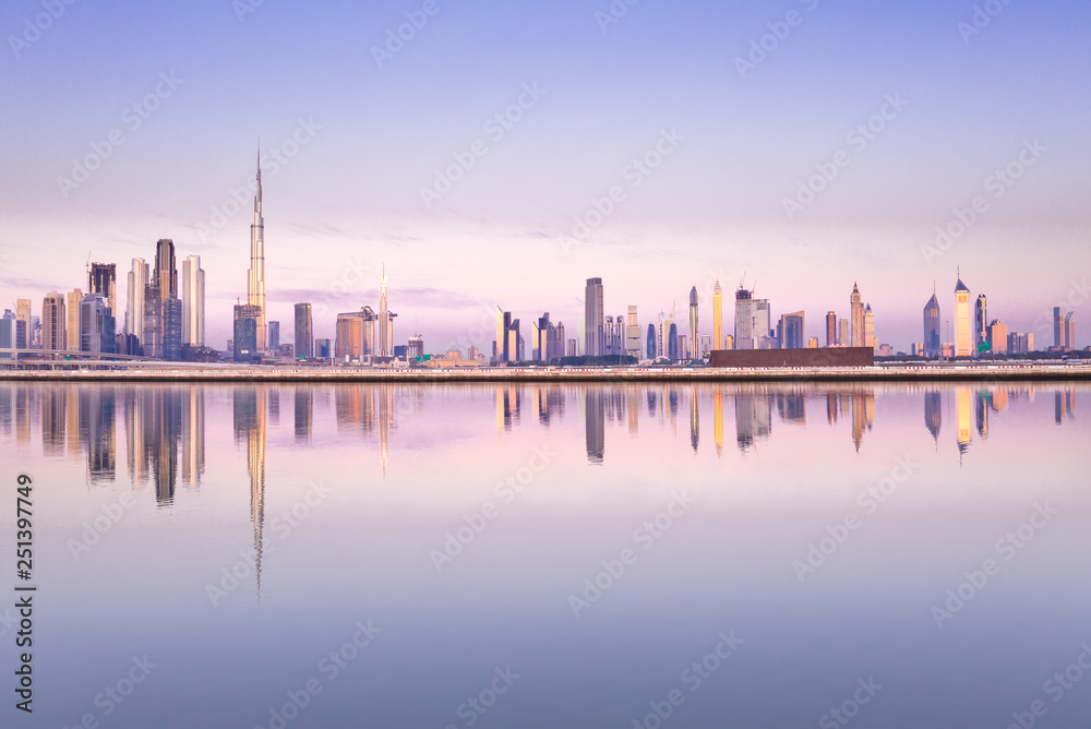 Beautiful colorful purple and pink sunrise lighting up the skyline and the reflection of Dubai Downtown. Dubai, United Arab Emirates.