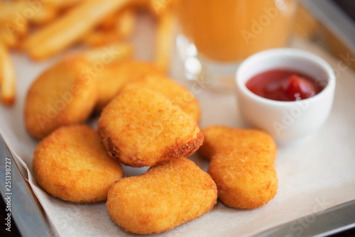 Close up chicken nuggets and fries with sauce and juice on plate