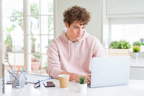 Young student man working and studying using computer laptop with a confident expression on smart face thinking serious