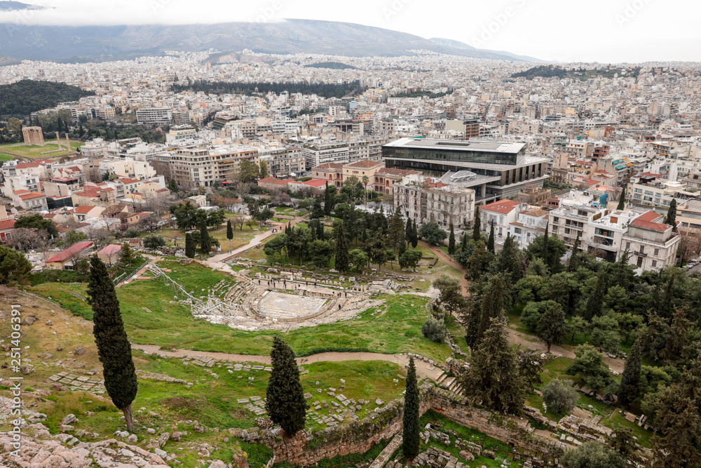 Athens, Greece - February 23, 2019: Panoramic view of Theatre of Dionysus and New Acropolis Museum on the urban background from Acropolis site of Athens, Greece.