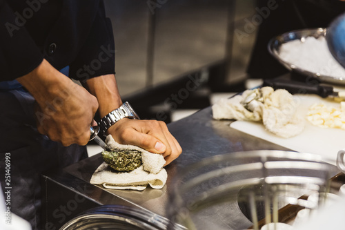 Billede på lærred Chef shucking a fresh oyster by knife on stainless steel counter bar