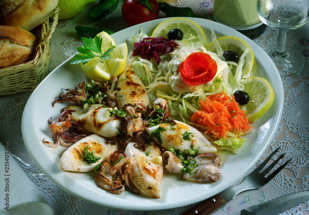 Plato con calamares a la plancha con ajo y perejil, y ensalada. Stock Photo  | Adobe Stock