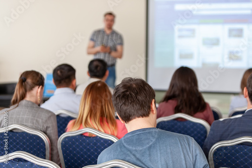 Spectators listen to the speech in the conference room. The focus is under the person on the front surface