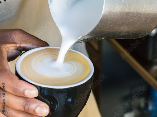 pouring microfoam to make latte art in a cappuccino flat white