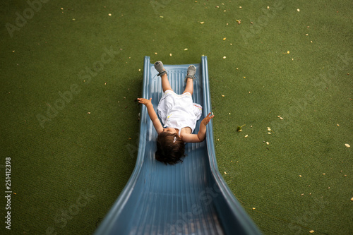 Niña jugando en un tobogan de un parque photo