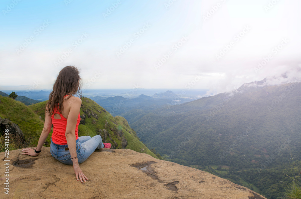 Naklejka premium Young beautiful woman in the mountains, enjoying the view and beauty of nature.