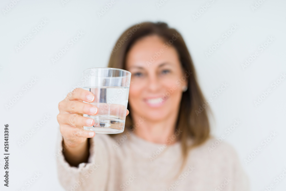 Middle age woman drinking glass of water isolated background with a happy face standing and smiling with a confident smile showing teeth Middle age woman drinking glass of water isolated background with a happy face standing and smiling with a confident smile showing teeth