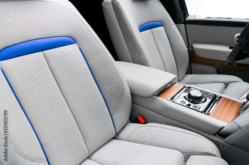 Modern luxury car white leather interior with natural wood panel. Part of leather car seat details with stitching. Interior of prestige modern car. White perforated leather. Car detailing. Car inside © Aleksei