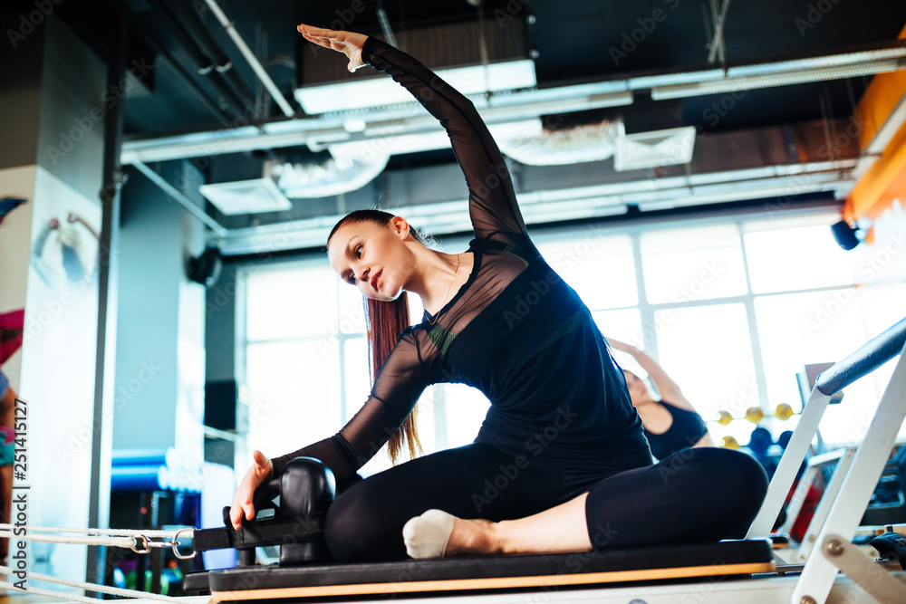 Εκτύπωση καμβά Two young females doing reformer exercises on pilates machines