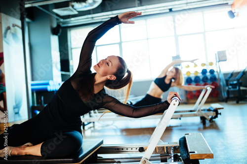 Two young females doing reformer exercises on pilates machines photo