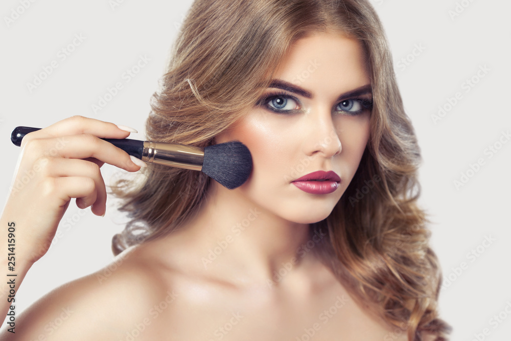The Makeup artist paints powder on the girl's face, completes the day's make-up in the beauty salon. Professional skin care. The Makeup artist paints powder on the girl's face, completes the day's make-up in the beauty salon. Professional skin care.