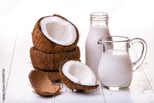 on the white table, carafe and bottle with coconut milk, parts of stacked coconuts