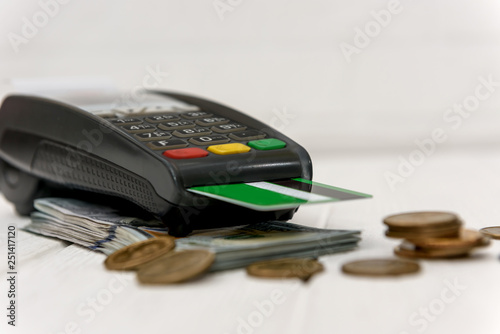 Dollars with coins and banking terminal with credit card