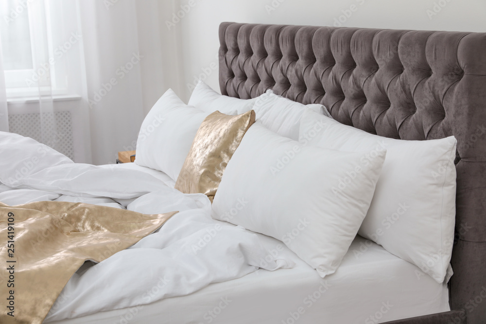 Soft pillows on comfortable bed in room. Modern interior design