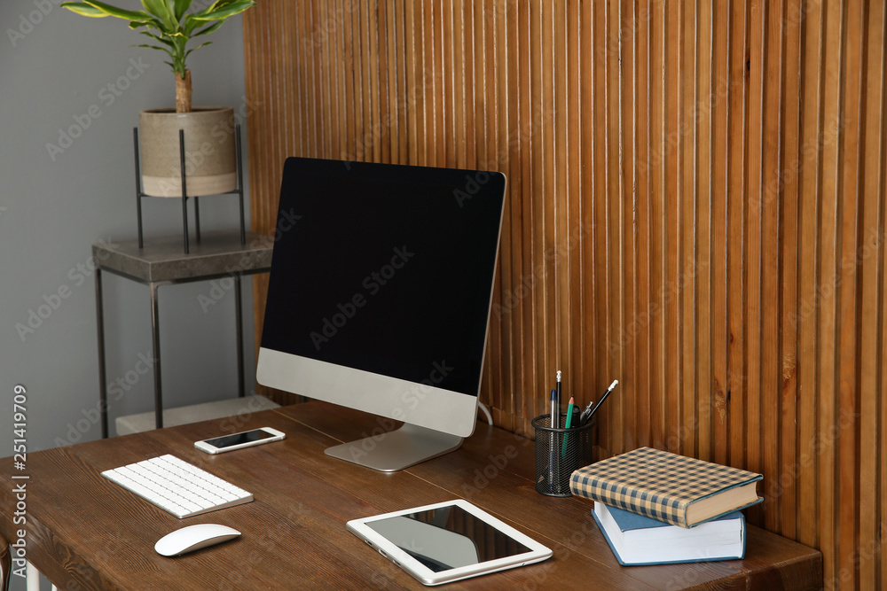 Stylish workplace with modern computer near wooden wall. Space for text Stylish workplace with modern computer near wooden wall. Space for text