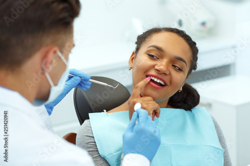 Woman  sitting in dentist chair  showing which tooth disturbing to doctor.