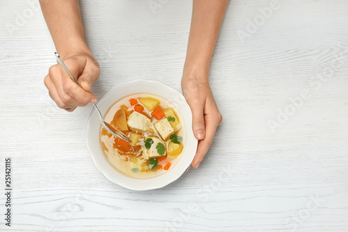 Woman eating fresh homemade chicken soup at table, top view. Space for text © New Africa