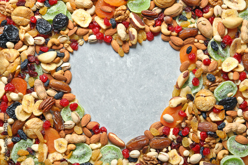 Fototapeta Naklejka Na Ścianę i Meble -  Heart shaped frame of different dried fruits and nuts on color background, top view. Space for text