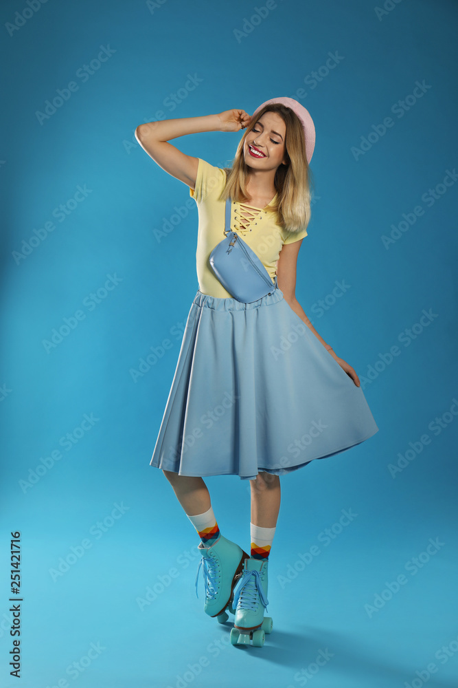 Naklejka premium Young woman with retro roller skates on color background