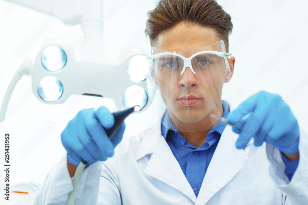 Front view of serious dentist wearing with dental equipment in hand. Front view of serious dentist wearing with dental equipment in hand.