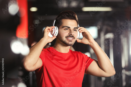 Young man listening to music with headphones at gym
