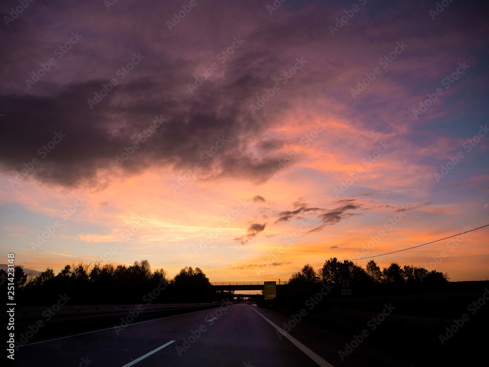 Driving on german autobahn on a beautiful sunset with magenta purple and ornage tones