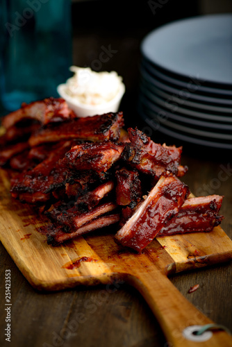 Smoked ribs ready to be eaten on wooden plate.​