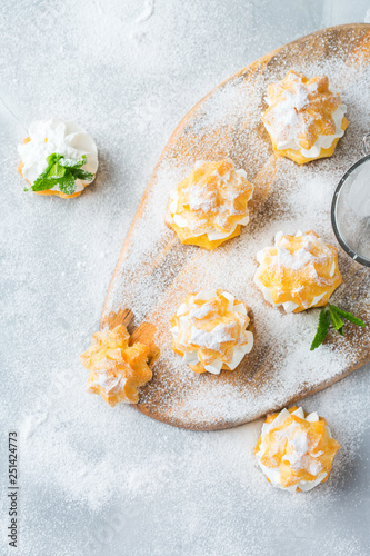 Delicious sweet profiteroles with cream on a modern kitchen table