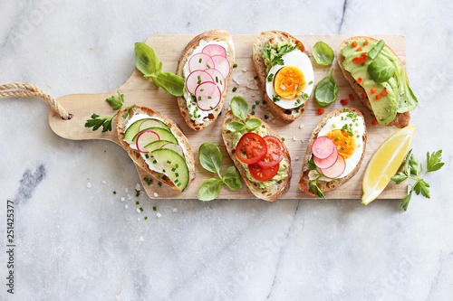 Fotografering Breakfast sandwich bread with avocado, egg, radishes and tomatoes