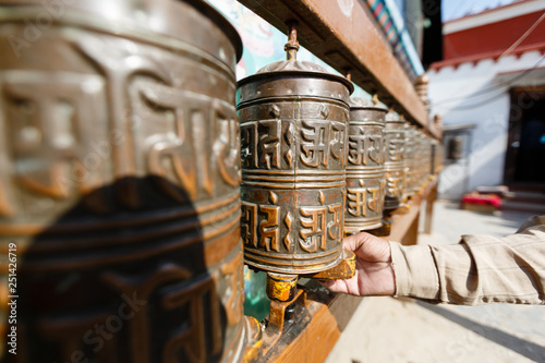 Nepal. Tibetan prayer wheels in Boudhanath. Hand turns the wheel. Center in focus. Background blurred