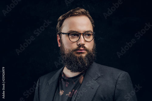 Close-up portrait of a smart bearded man in glasses in a dark studio