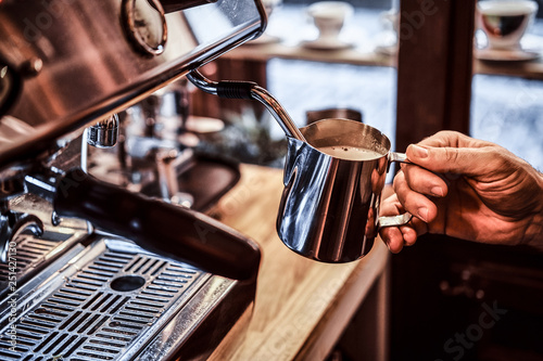 The barista working on steam espresso coffee machine in a coffee shop