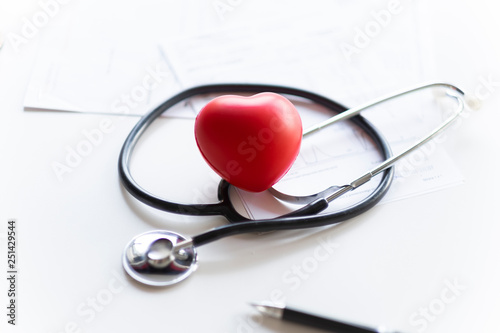 Stethoscope and heart lying on the white desk.