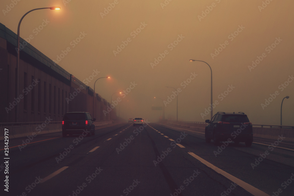 Highway in mystic fog mist smog. Cars on freeway road at evening in american city country. Poor visibility in bad weather conditions. Toned with retro film hipster filters. Dangerous suspense