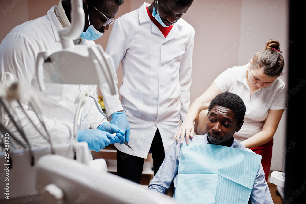 Multiracial dentist doctors team. African american man patient preparing for surgery. Multiracial dentist doctors team. African american man patient preparing for surgery.