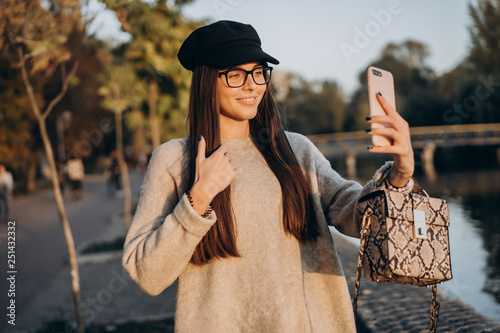 Cheerful young girl at the park, taking a selfie photo