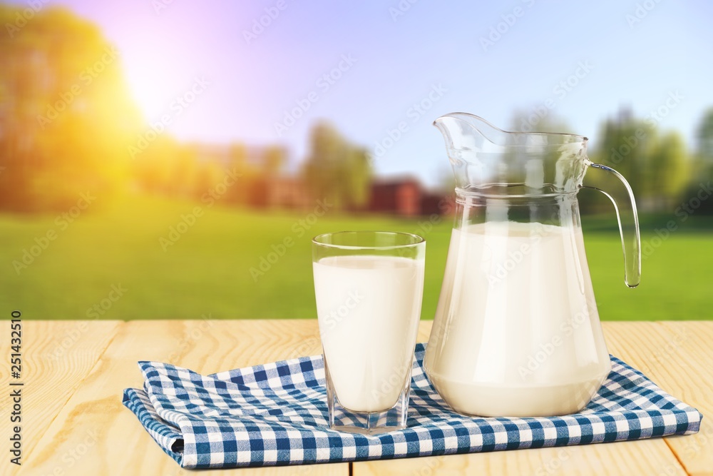 Glass of milk and jug on blurred background Glass of milk and jug on blurred background