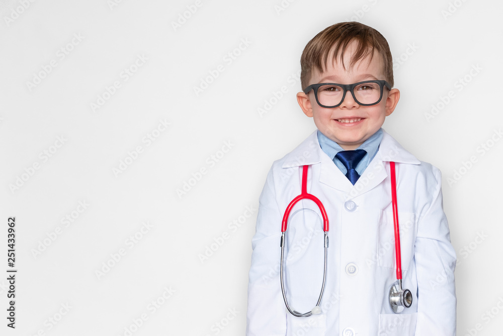 Smiling little boy in medical uniform wearing a stethoscope and looking at camera isolated on white