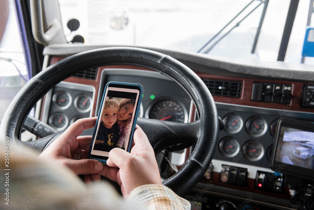 Hands of truck driver holding smart phone with photograph of his children Hands of truck driver holding smart phone with photograph of his children