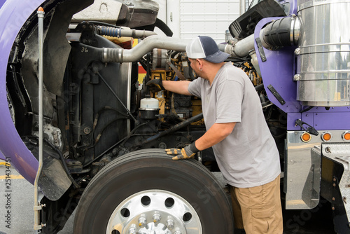 Truck driver checking semi-truck engine photo
