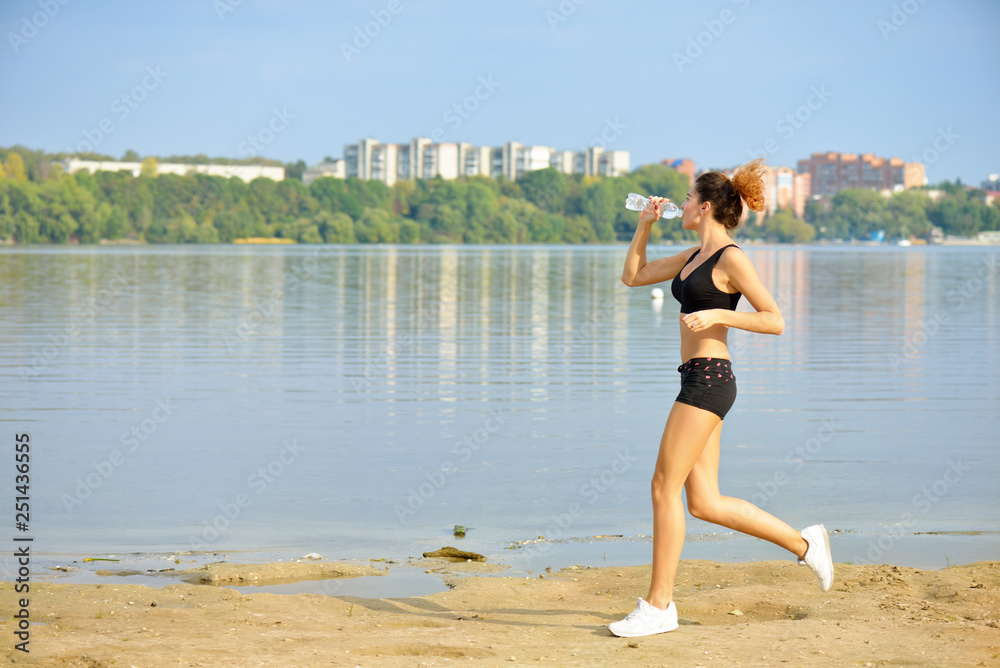 Running woman. Female runner jogging during outdoor workout on beach. Sport model outdoors. Fitness Concept.