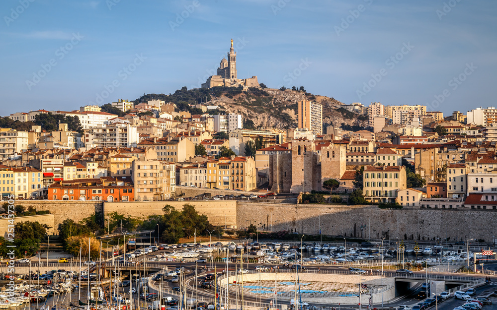 Panoramic cityscape of Marseille with the church Notre-Dame de la Garde, landmark of the city,  on a hilltop at sunset. Marseille, Provence, France. Holidays in France.